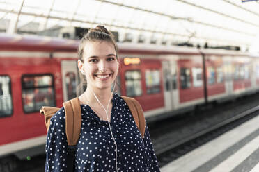 Porträt einer lächelnden jungen Frau auf dem Bahnhof - UUF18300