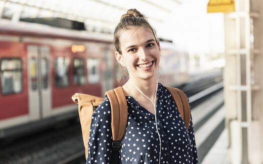 Porträt einer lächelnden jungen Frau auf dem Bahnhof - UUF18301