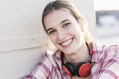 Porträt einer lächelnden jungen Frau mit Kopfhörern, lizenzfreies Stockfoto