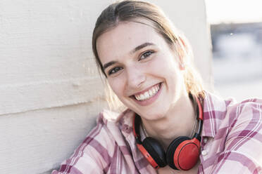 Porträt einer lächelnden jungen Frau mit Kopfhörern - UUF18325