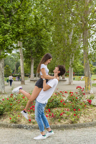 Junges Paar in einem Park, Mann hebt die Frau hoch, lizenzfreies Stockfoto