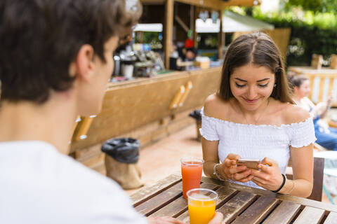 Junges Paar in einem Café, Frau benutzt Smartphone, lizenzfreies Stockfoto