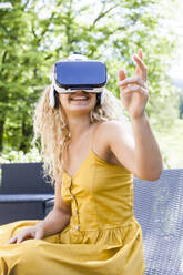 Young blond woman using virtual reality glasses outdoors - TCF06158