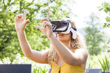 Junge blonde Frau mit Virtual-Reality-Brille im Freien - TCF06159