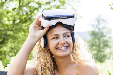 Junge blonde Frau mit Virtual-Reality-Brille im Freien, seitwärts blickend - TCF06160