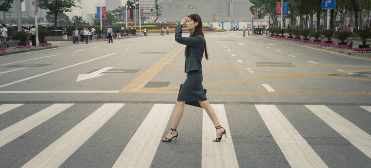 Chinesische Geschäftsfrau auf dem Fußgängerüberweg - BLEF12050