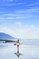Mann trägt Surfbrett am Strand - BLEF12075