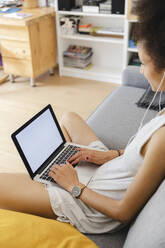 Young woman using her laptop on the sofa - MRAF00409