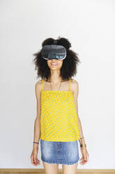 Young woman wearing virtual reality glasses, white background - MRAF00413