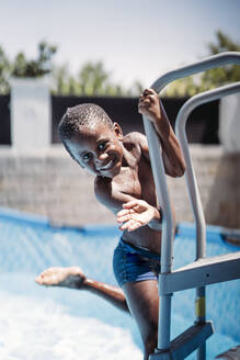 Glücklicher kleiner Junge auf einer Leiter im Schwimmbad - OCMF00524