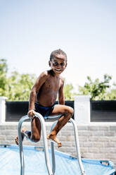 Glücklicher kleiner Junge auf einer Leiter im Schwimmbad - OCMF00525