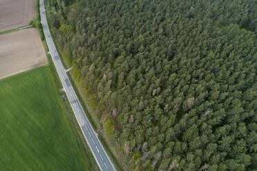 Aerial view of road between forest and agricultural fields, Franconia, Bavaria, Germany - RUEF02271