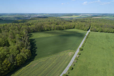 Luftaufnahme einer Straße durch landwirtschaftliche Felder und Wald, Franken, Bayern, Deutschland, lizenzfreies Stockfoto