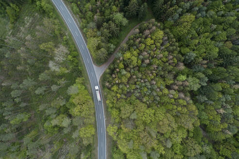 Aerial view of rural road through forest, Franconia, Bavaria, Germany - RUEF02289