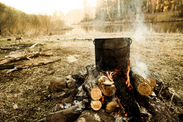 Pot cooking on campfire in rural field - BLEF12090