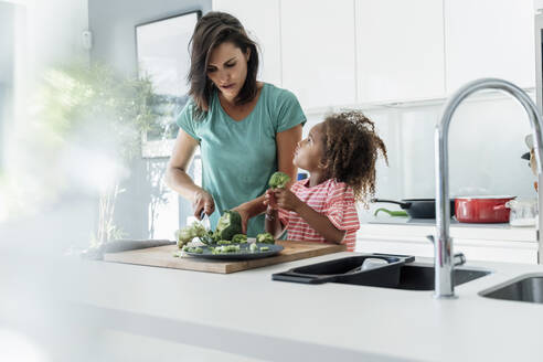 Mutter und Tochter kochen gemeinsam in der Küche und schneiden Brokkoli - ERRF01666