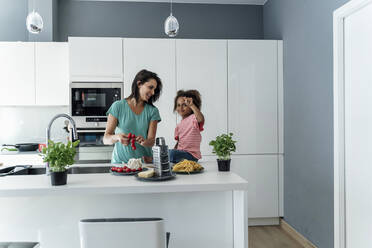 Mother and daughter cooking in kitchen together - ERRF01670