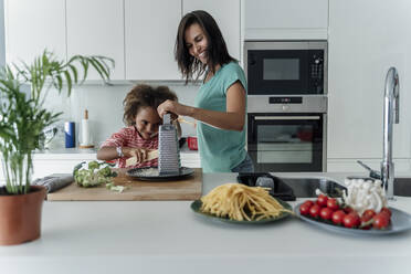 Mutter und Tochter kochen gemeinsam in der Küche und reiben Käse - ERRF01685