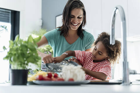 Glückliche Mutter und Tochter beim gemeinsamen Kochen in der Küche, lizenzfreies Stockfoto