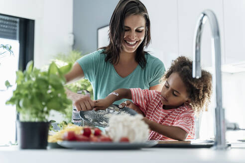 Glückliche Mutter und Tochter beim gemeinsamen Kochen in der Küche - ERRF01688