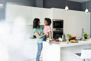 Happy mother holding daughter in kitchen - ERRF01708