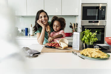 Porträt einer glücklichen Mutter und Tochter, die gemeinsam in der Küche kochen - ERRF01710