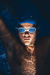 Porträt einer jungen paralympischen Schwimmerin, die in einem Schwimmbecken auf dem Wasser schwimmt - JCMF00074