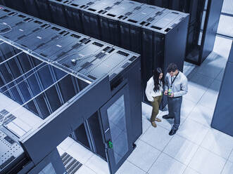 High angle view of technicians talking in server room - BLEF12185