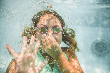 Caucasian girl holding nose underwater in swimming pool - BLEF12202