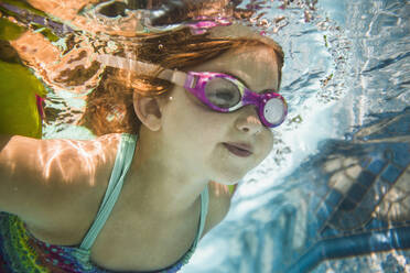 Kaukasisches Mädchen schwimmt unter Wasser im Schwimmbad - BLEF12203