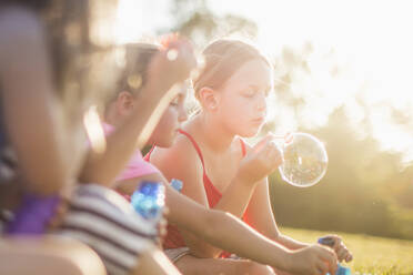 Girls blowing bubbles in grass field - BLEF12211