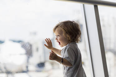 Caucasian baby boy looking out airport window - BLEF12219