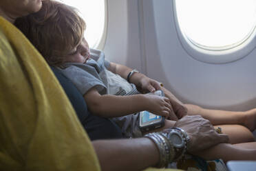 Caucasian mother holding baby son on airplane - BLEF12220