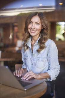 Business woman using laptop in a cafe - PNEF01745