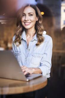 Business woman using laptop in a cafe - PNEF01748