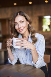 Geschäftsfrau mit einer Tasse Kaffee in einem Cafe - PNEF01749