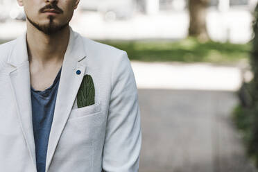 A handsome hipster young man with formal suit standing by a window