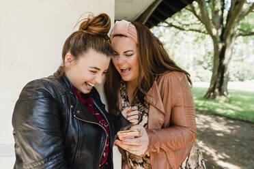 Zwei lachende Freunde schauen auf ihr Handy - NMS00350