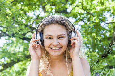 Smiling young woman listening to music, looking at camera - TCF06175