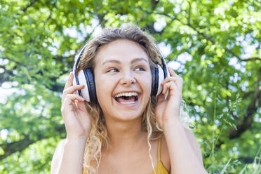 Smiling woman listening to music, looking sideways - TCF06176