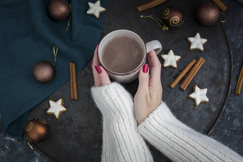 Frauenhände halten eine Tasse heiße Schokolade zur Weihnachtszeit, lizenzfreies Stockfoto