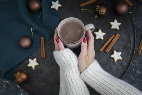 Frauenhände halten eine Tasse heiße Schokolade zur Weihnachtszeit - JUNF01694