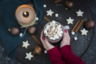 Frauenhände halten eine Tasse heiße Schokolade mit Marshmellows zur Weihnachtszeit - JUNF01697