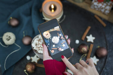 Woman's hand taking picture of cup of Hot Chocolate with marshmellows with smartphone - JUNF01699