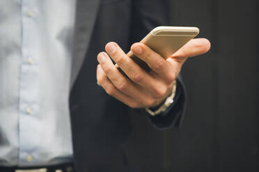 Hand of businessman holding mobile phone, close-up - JUNF01706