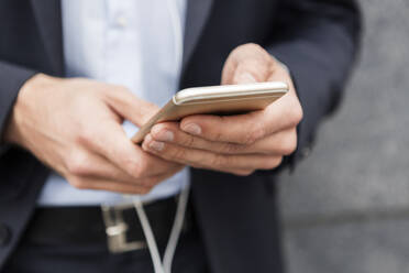 Hände eines Geschäftsmannes, der ein Mobiltelefon hält, Nahaufnahme - JUNF01713