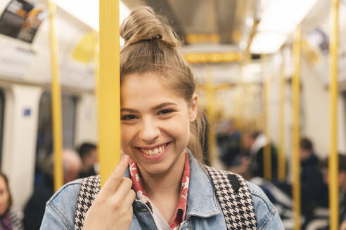 Porträt einer lächelnden jungen Frau in der U-Bahn - WPEF01633