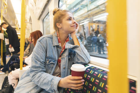 Junge Frau fährt mit dem Zug und schaut aus dem Fenster, lizenzfreies Stockfoto