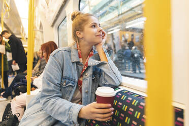 Junge Frau fährt mit dem Zug und schaut aus dem Fenster - WPEF01634