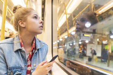 Young woman travelling by train and looking out of the window - WPEF01635